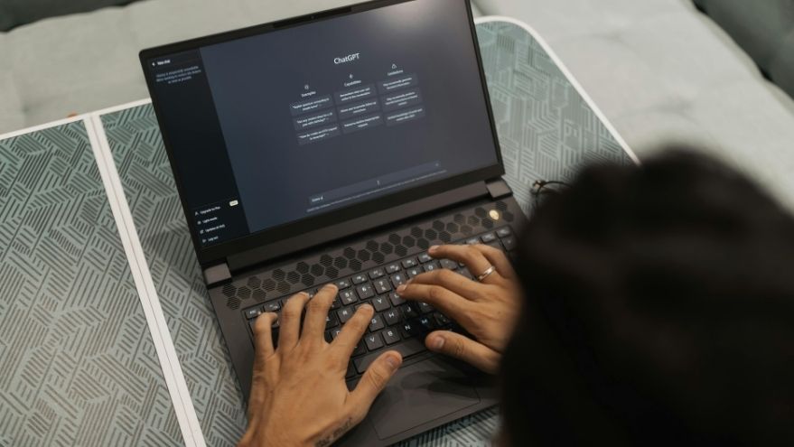 K business professional using AI software on laptop demonstrating workplace AI adoption.