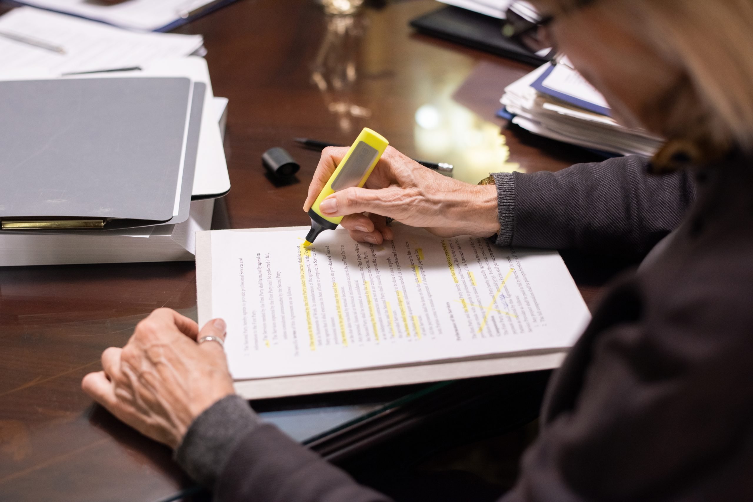 Hands of leader with yellow highlighter underlining the main terms of contract or other document